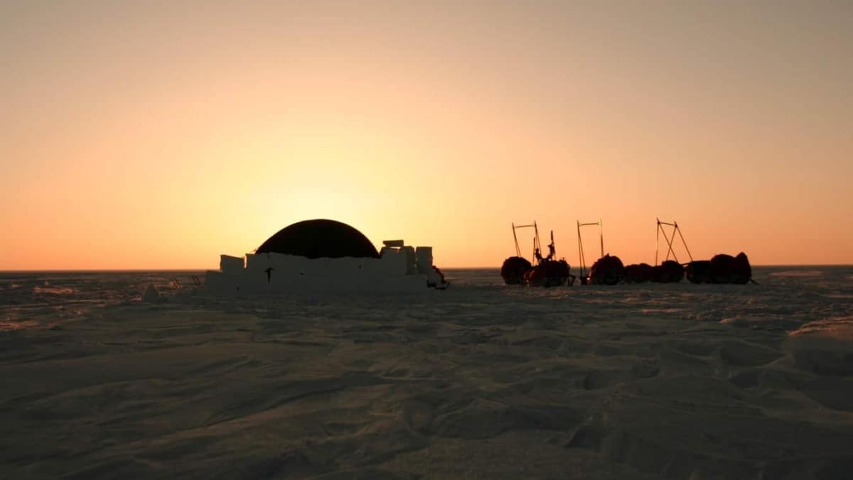 Tent in de sneeuw tijdens zonsondergang