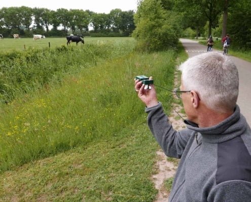 Nico van Vondelen over de Navigeren met kaart en kompas workshop in Nederland 8 Een man met grijs haar en bril staat langs een verhard pad en richt zijn camera op grazende koeien in een groen veld. Wilde bloemen en hoog gras sieren het pad, terwijl bomen de achtergrondvormen. Voor hem fietst iemand, mogelijk met een kaart voor navigatie.Op zoek naar avontuur? Ontdek prachtige fietsroutes, groene weides en betoverende landschappen! Voel je vrij in de natuur en leg momenten vast!
