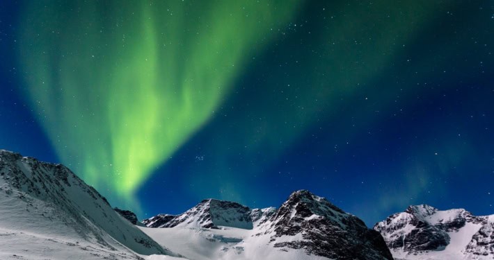 Ervaar de sensatie van avontuur onder het majestueuze groene noorderlicht dat de besneeuwde toppen van Kebnekaise, Zweden, verlicht.