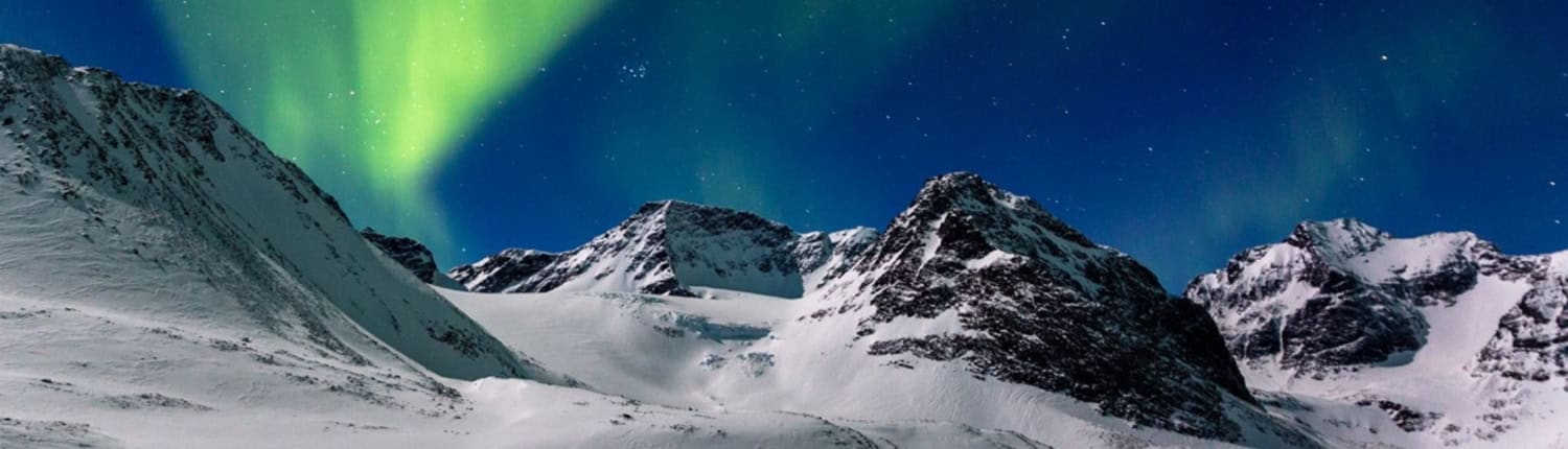 Met sneeuw bedekte bergen, waaronder de Kebnekaise, de hoogste berg van Zweden, liggen onder een helder, groen noorderlicht met een heldere sterrenhemel.