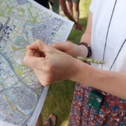 Kaart en kompas navigatie workshop_25 Een avontuur met een stadsgids en een grassprietverkent de stad op een zonnige dag. Met een groene badge om de nek en mede-avonturiers op de achtergrond beleef je buiten het ultieme avontuur!