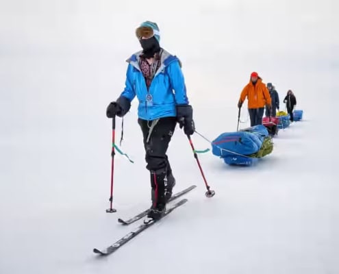 Mensen op skislede met sleds door besneeuwd landschap.