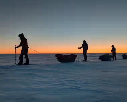 Gestructureerde sleeptochten onder een kleurrijke zonsondergang in de ijswoestijn.