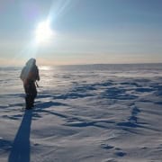 Wandelaar in de sneeuw onder de zon in Arctic Adventure outdoor workshop.