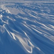 Silhouetten van sneeuwdriften in daglicht op ijslandschap.
