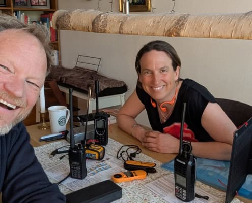 Two people laughing and talking with walkie-talkies in a cozy indoor space.
