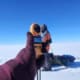 Snow measurement with weather station on ice plain under clear blue sky.