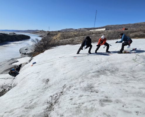 Three people pulling pulks across the Greenland ice plain during an expedition.
